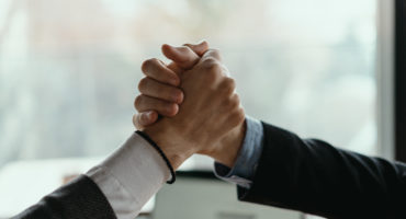 Close up two businessmen shaking hands. Positive management team celebrating victory, successful stock deal, sales growth, won good contract